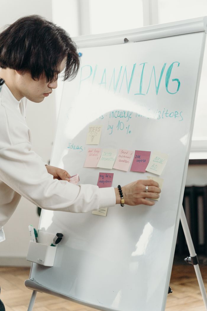 project-02-d A professional engaged in a brainstorming session, organizing ideas on a whiteboard with sticky notes.